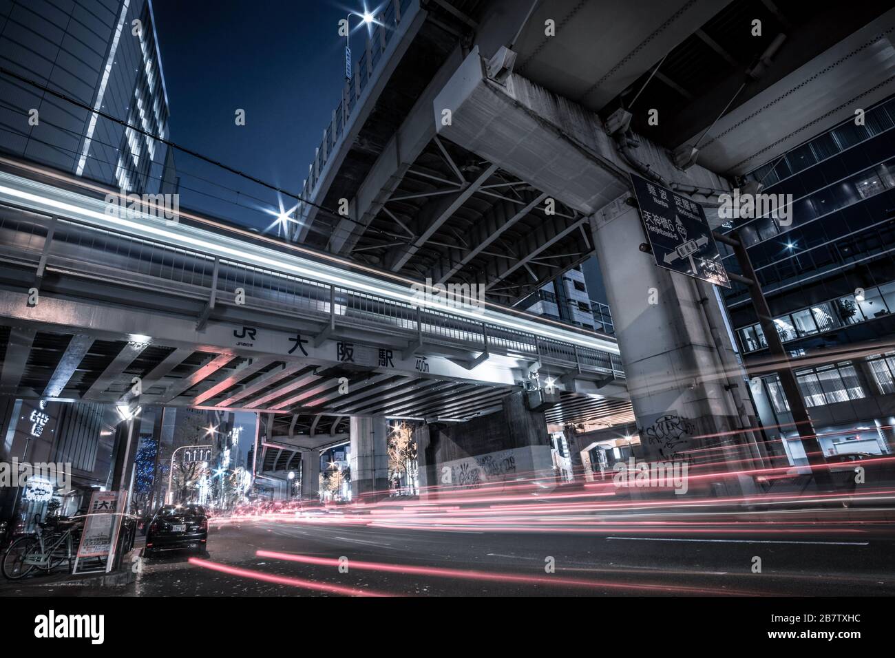 Long exposure night view of traffic and a train moving under an elevated highway in Osaka, Japan. Stock Photo