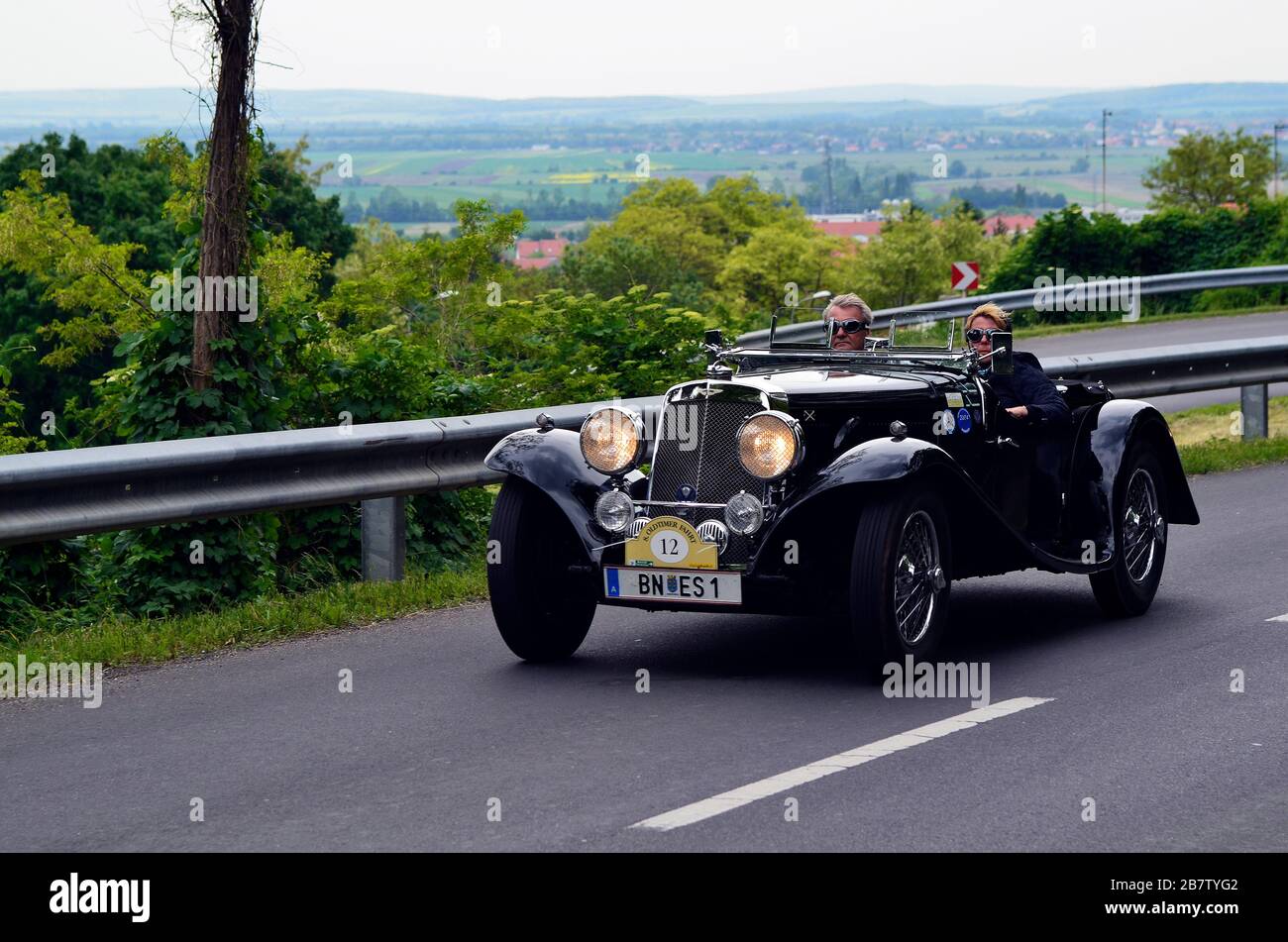 Eisenstadt, Austria - May 14th 2011: Unidentified couple in Aston Martin on 8th Oldtimer Fahrt - a yearly competition for vintage cars on special stag Stock Photo