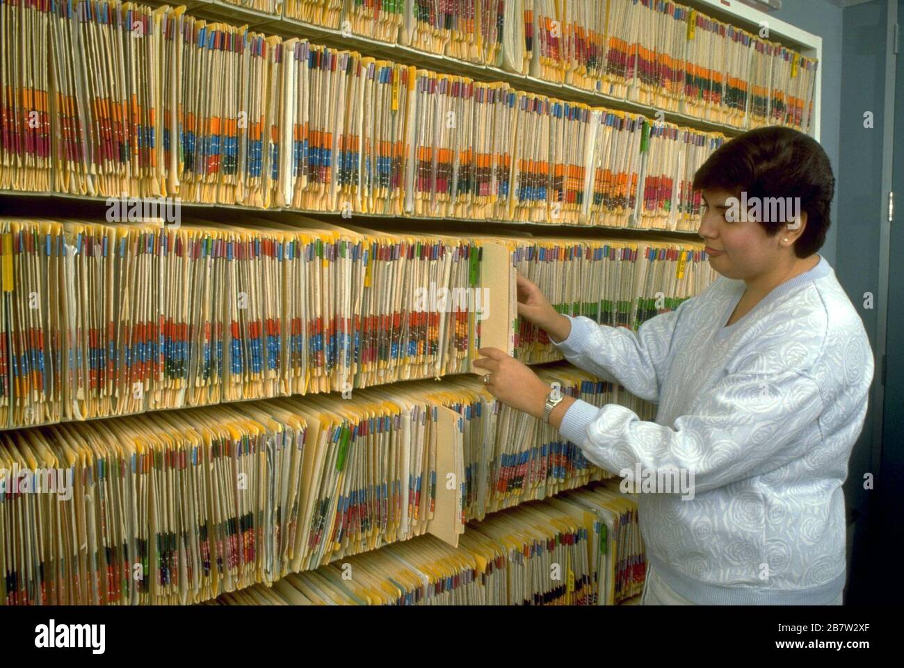 Nurse in doctor's office files colorcoded paper patient records. ©Bob Daemmrich Stock Photo Alamy