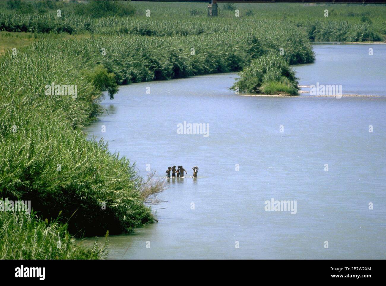 Laredo Texas USA: Migrants wading into the Rio Grande on the Mexican side ready to cross illegally into the United States near Laredo.   ©Bob Daemmrich Stock Photo