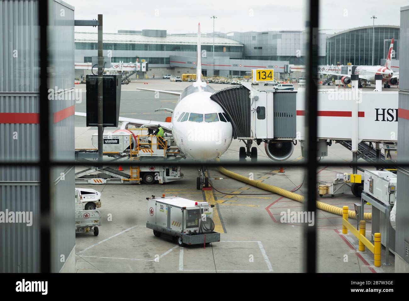 A colour landscape image showing a passenger jet at the gate at an airport. Stock Photo