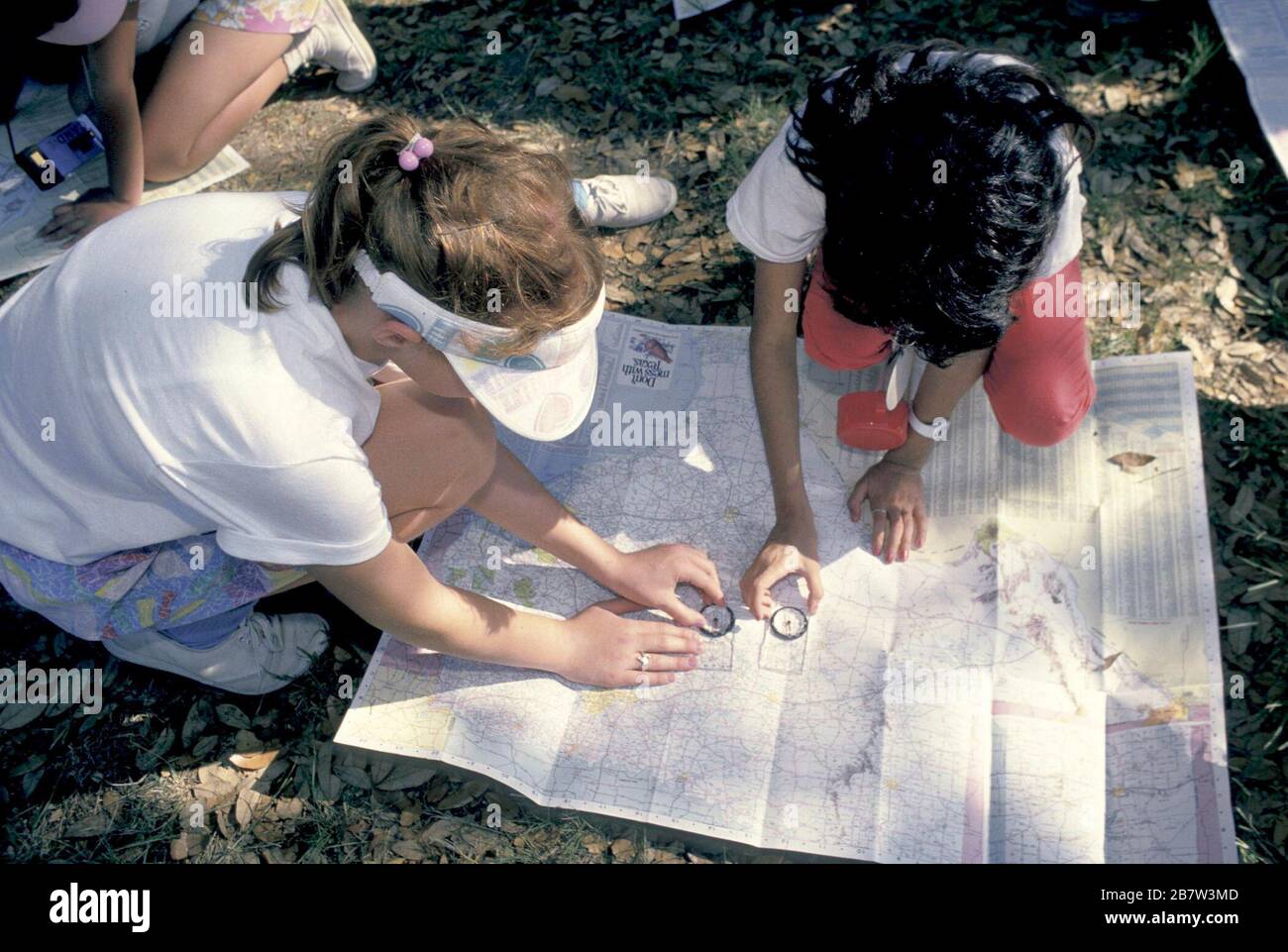 Bandera, Texas USA, circa 1991: Fourth grade girls use compass and map  to estimate their location during an overnight school camping trip.   ©Bob Daemmrich Stock Photo