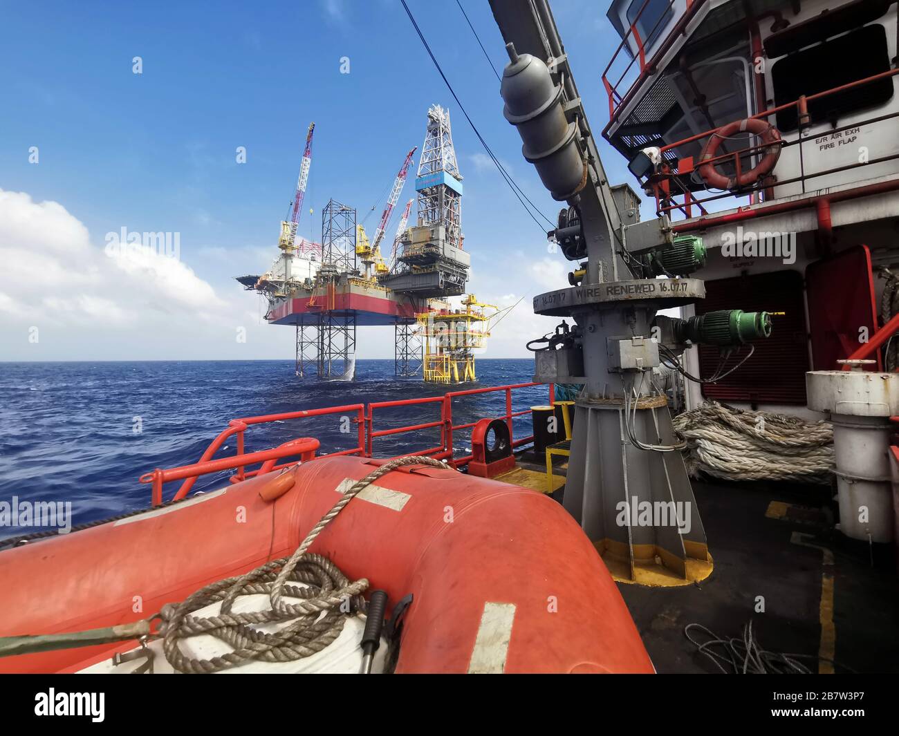 jack up rig and oil platform drilling at sea with rescue bot and crane from ship Stock Photo