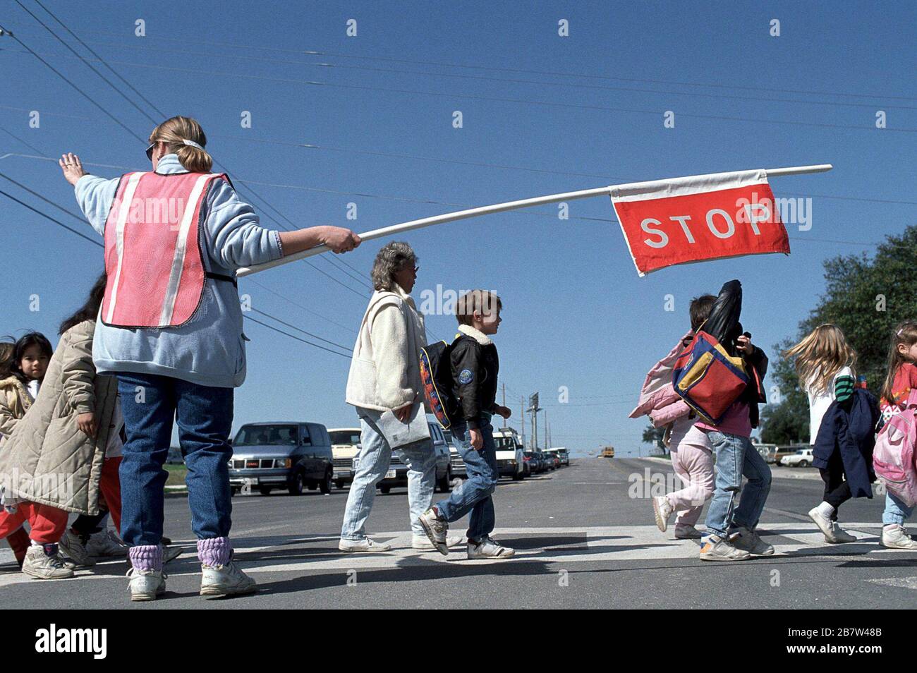 Austin, Texas USA:  Adult crossing guard stops traffic while students and parents cross street outside of Walnut Creek elementary school. ©Bob Daemmrich Stock Photo