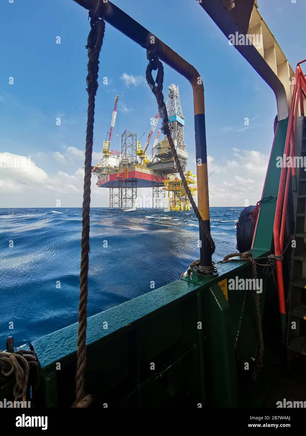 jack up rig and oil platform drilling at sea with rescue bot and crane from ship Stock Photo