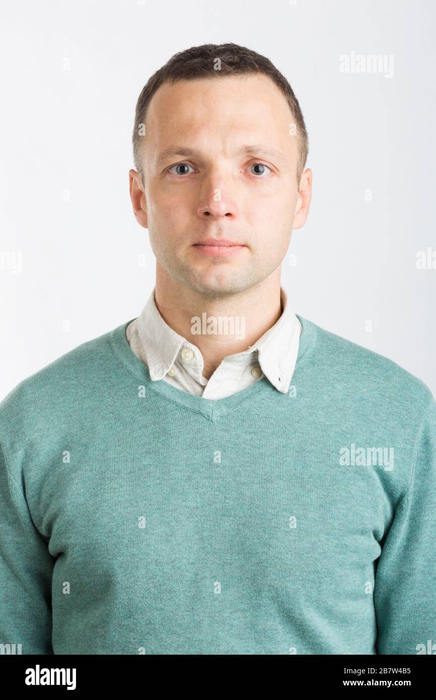 Young serious Caucasian man in smart casual clothing, studio face portrait over white wall background Stock Photo