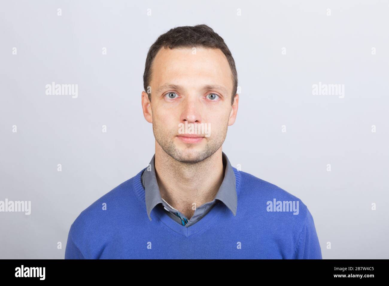 Young serious European man in smart casual clothing, studio face portrait over gray wall background Stock Photo