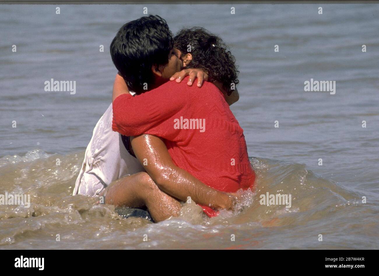 Young couple embraces in shallow water near beach at Texas Gulf coast.  ©Bob Daemmrich Stock Photo