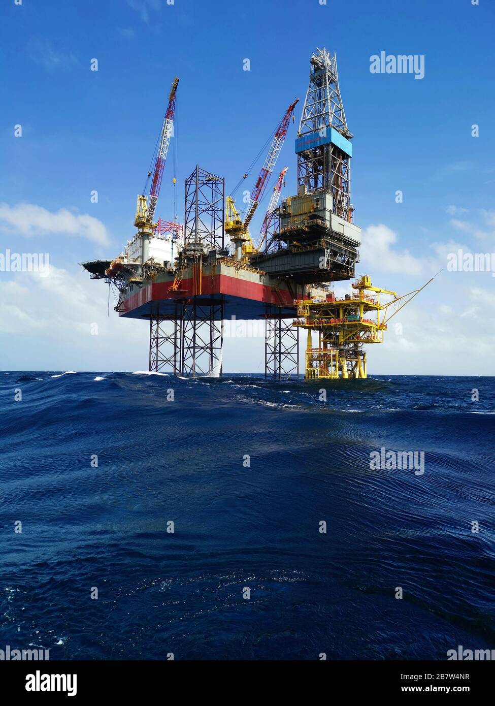 jack up rig with oil platform drilling at oil fields with beautiful blue cloudy sky at ocean Stock Photo