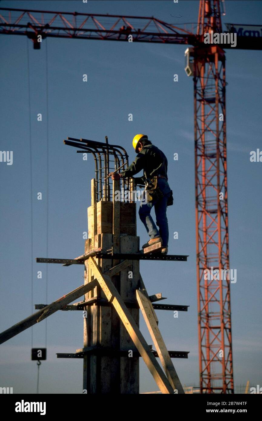 Worker wearing hard hat balances on scaffolding surrounding column during construction of large shopping mall.  ©Bob Daemmrich Stock Photo