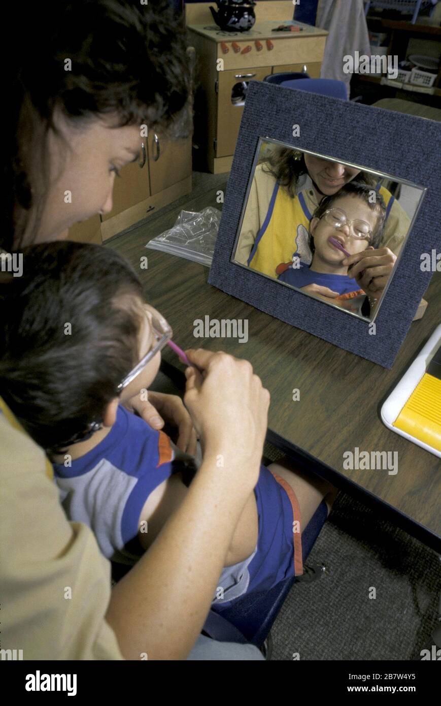 Occupational therapist teaching disabled child to brush his teeth and reduce his tactile defensiveness. MR ©Bob Daemmrich Stock Photo