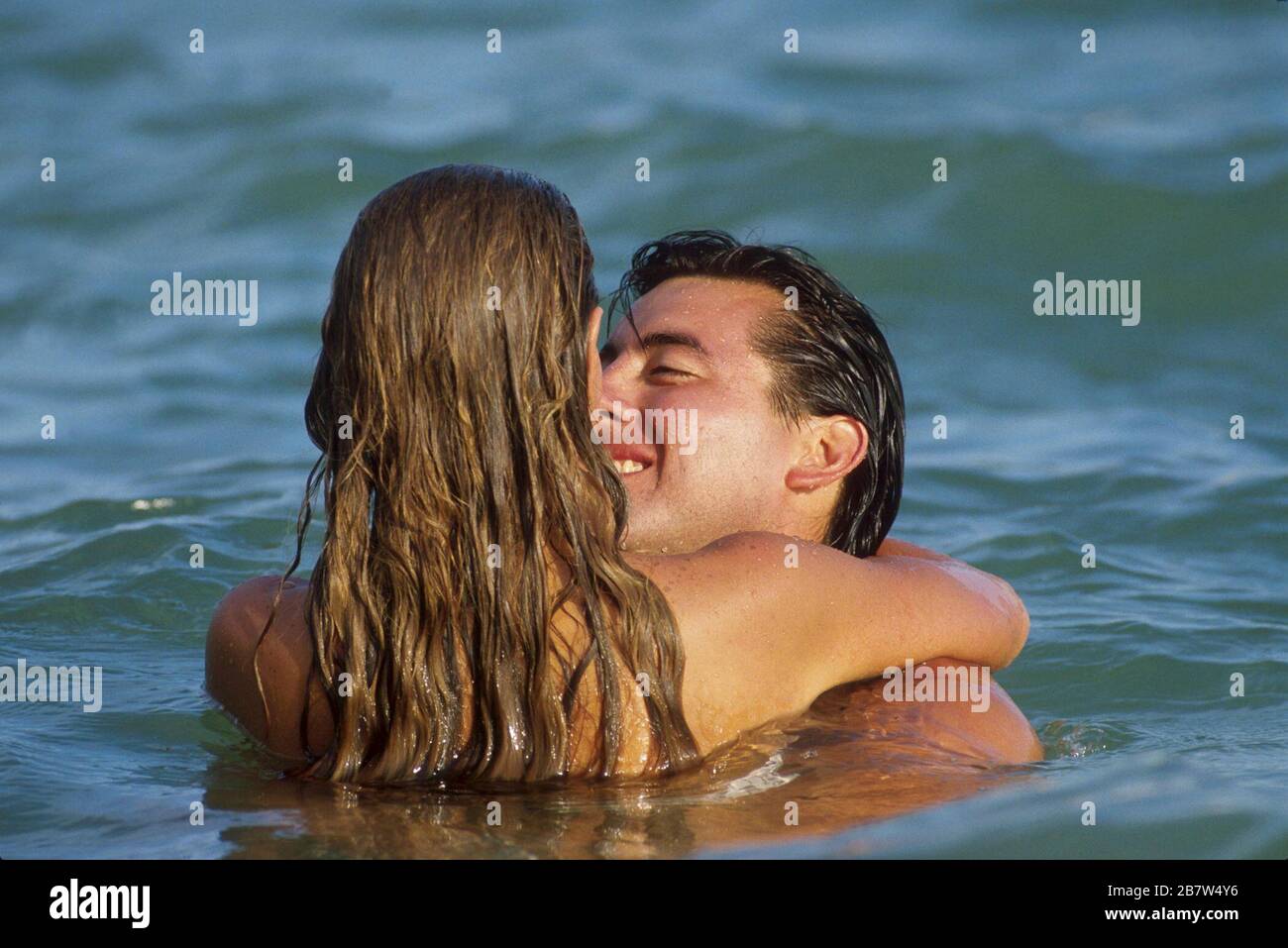 Young man and young woman embrace while swimming in lake. ©Bob Daemmrich Stock Photo