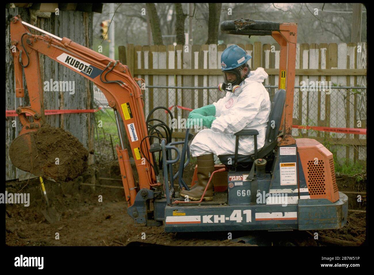 Austin Texas USA: Worker wearing protective gear uses a backhoe to remove lead from property in residential neighborhood.    ©Bob Daemmrich Stock Photo