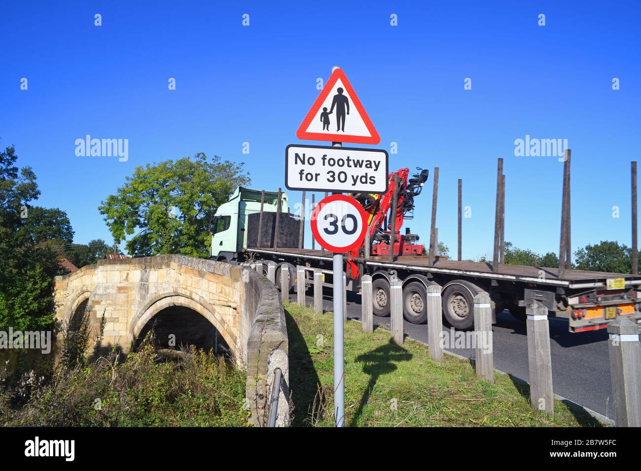 lorry passing no footway for pedestrians in road ahead warning sign on bridge crossing the river derwent at sutton on derwent united kingdom Stock Photo