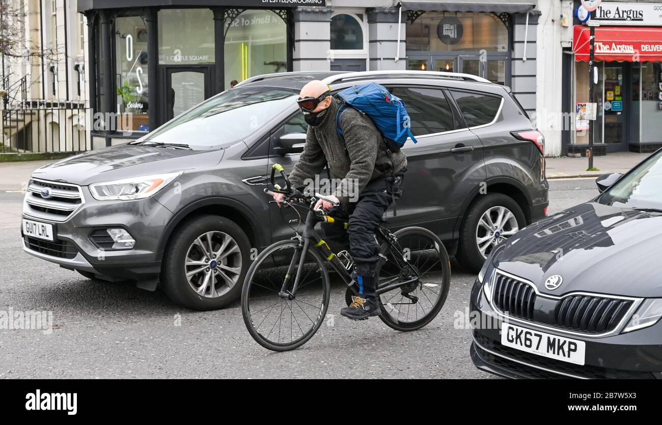 Brighton UK 18th March 2020 - A cyclist wearing a protective mask and goggles as the streets around Brighton are quieter than normal as people avoid coming into the city centre because of the Coronavirus COVID-19 pandemic crisis  . Credit: Simon Dack / Alamy Live News Stock Photo