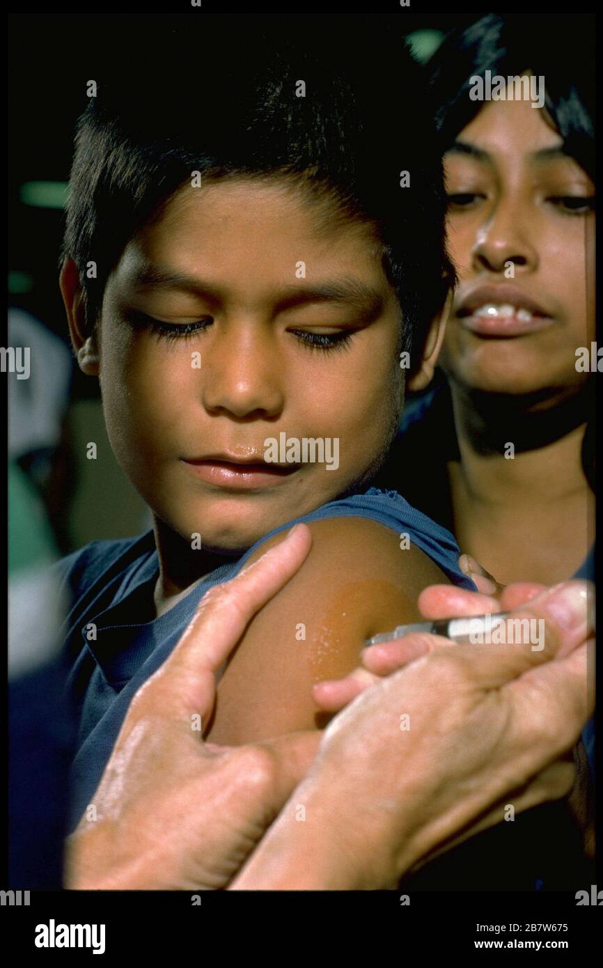 Austin Texas USA: Elementary school-aged boy sits in mother's lap while getting a shot in the arm at an inoculation clinic for children before the start of the school year.  MR   ©Bob Daemmrich Stock Photo