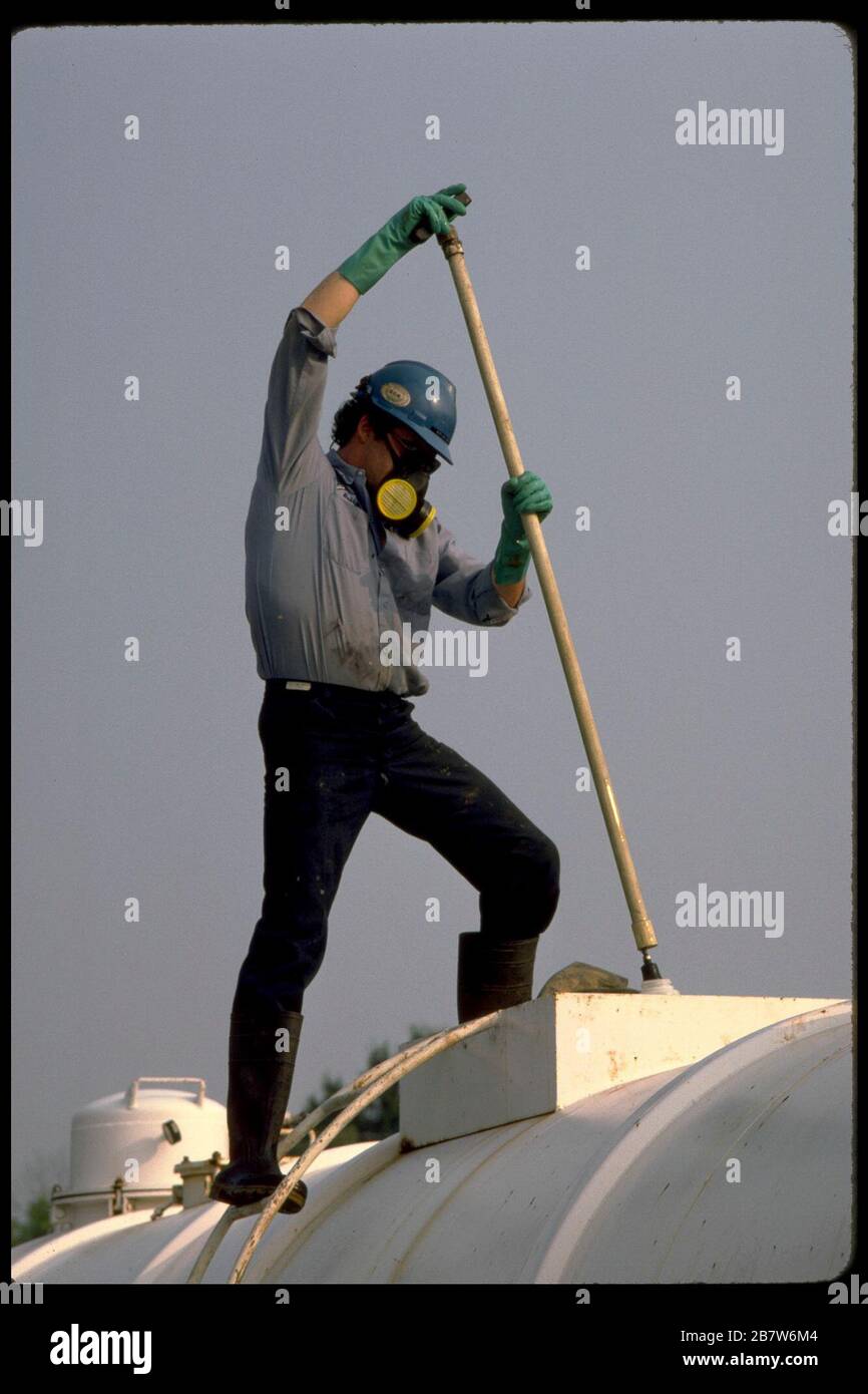 Worker wearing safety gear cleans container used to transport hazardous material.   ©Bob Daemmrich Stock Photo