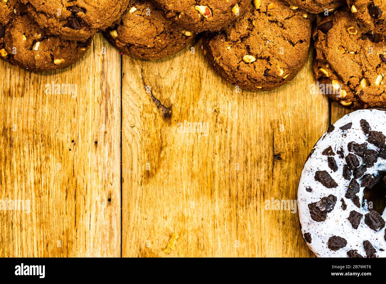 Frame made of chocolate chip cookies, biscuits and colorful donuts top view with copy space