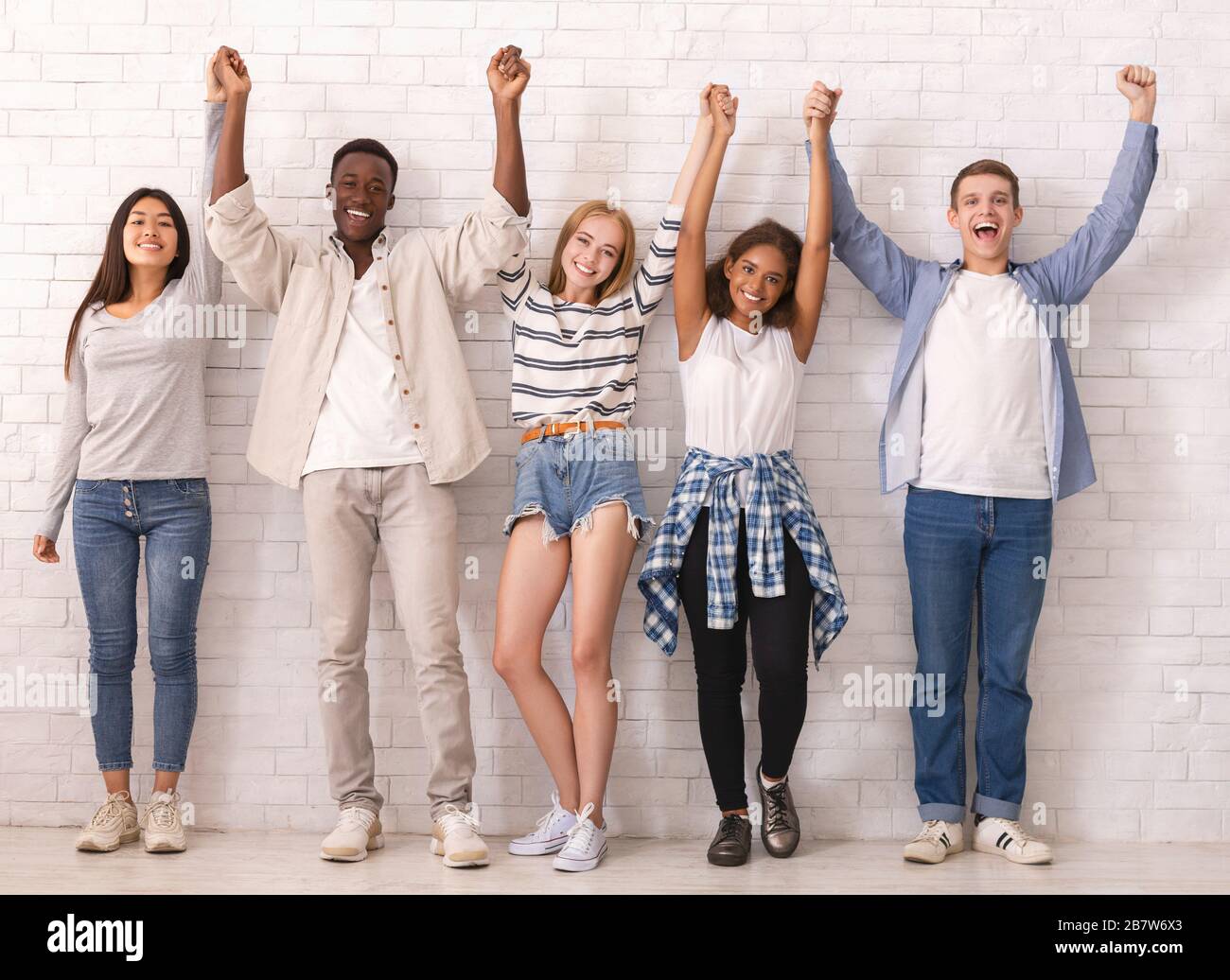 Joyful teenagers raising joined hands up together Stock Photo Alamy