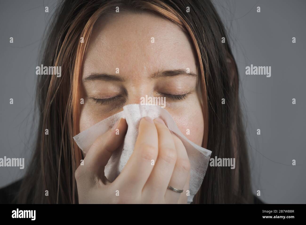 Sneezing, coughing or blowing nose in a single use paper towl. Concept of catching cold, virus or infection and not spreading it Stock Photo