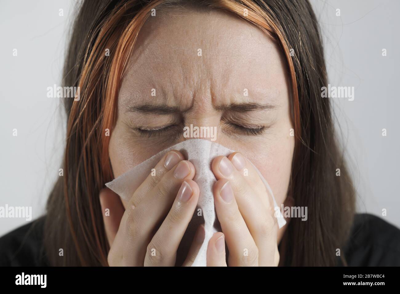 Sneezing, coughing or blowing nose in a single use paper towl. Concept of catching cold, virus or infection and not spreading it Stock Photo