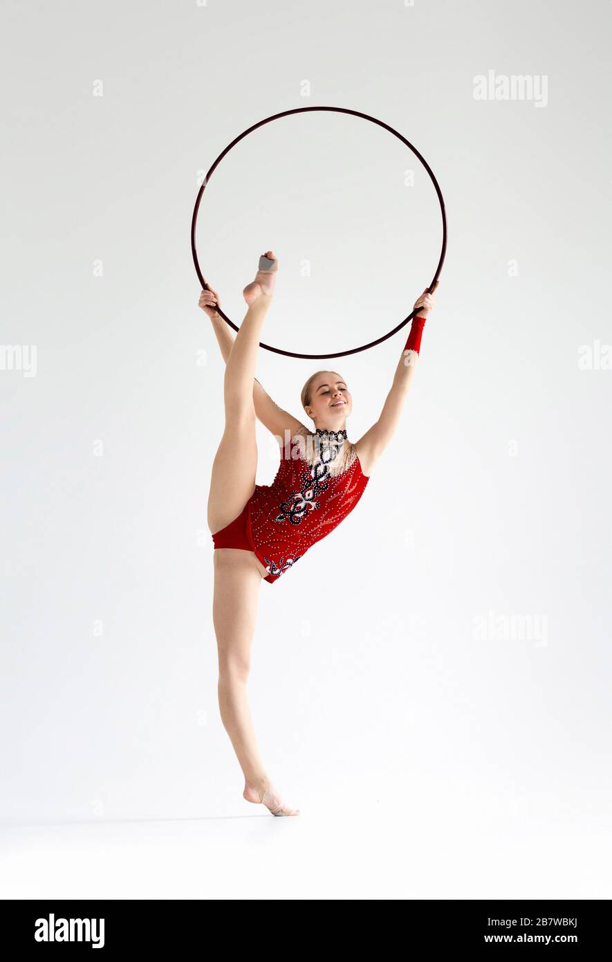 Professional athlete doing complicated gymnastic trick with hoop on white background Stock Photo