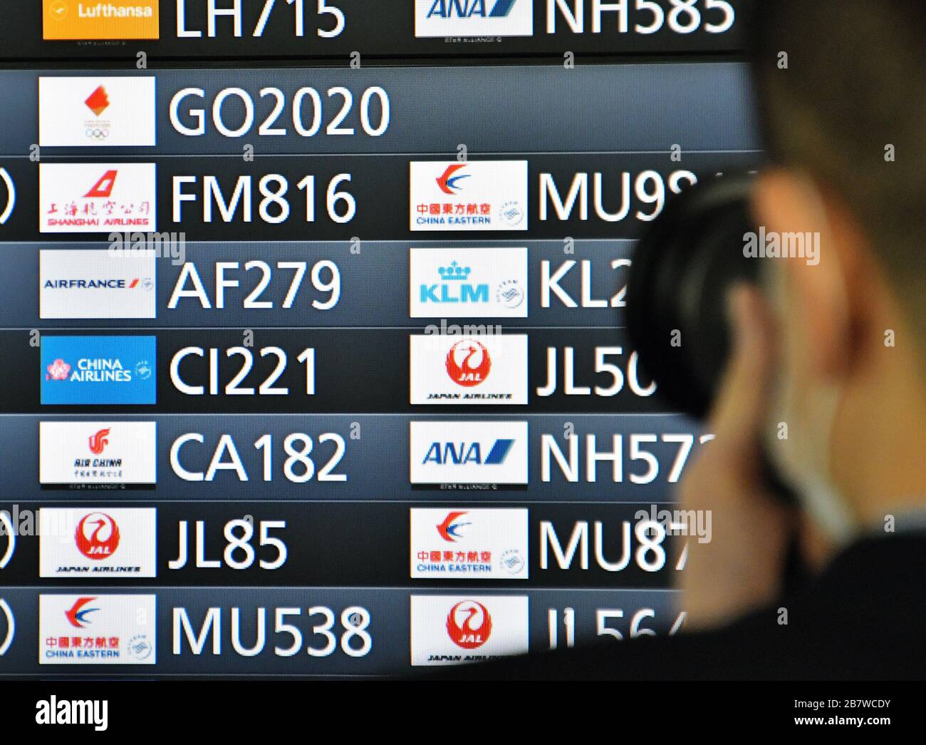 Tokyo, Japan. 18th Mar, 2020. Traveler takes photo the departure boards displayed flight 'GO2020' at Tokyo international airport in Japan on Wednesday, March 18, 2020. The Tokyo 2020 Olympic Torch Relay Special Aircraft 'Tokyo 2020 Go' transport the Olympic Flame from Greece, will land back at the Japan Air Self-Defense Force Matsushima Base in Miyagi-Prefecture, Japan on March 20. Photo by Keizo Mori/UPI Credit: UPI/Alamy Live News Stock Photo