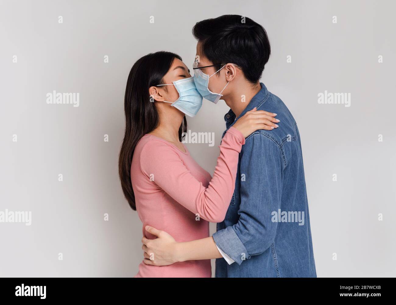 Romantic Asian Couple Kissing Each Other In Medical Face Masks Stock Photo