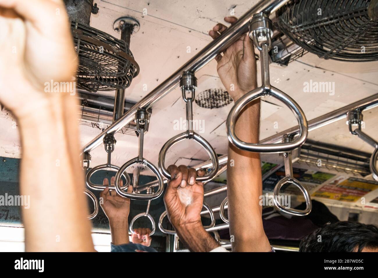 Passengers hands on hand rails on a busy Mumbai commuter train, India Stock Photo
