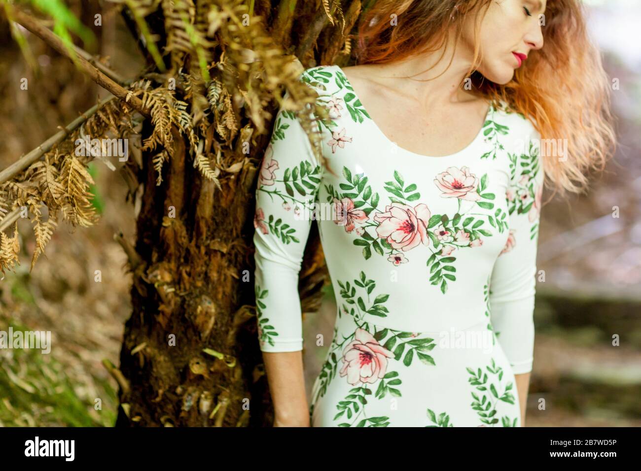 Woman in Floral Dress Standing by Tree Stock Photo