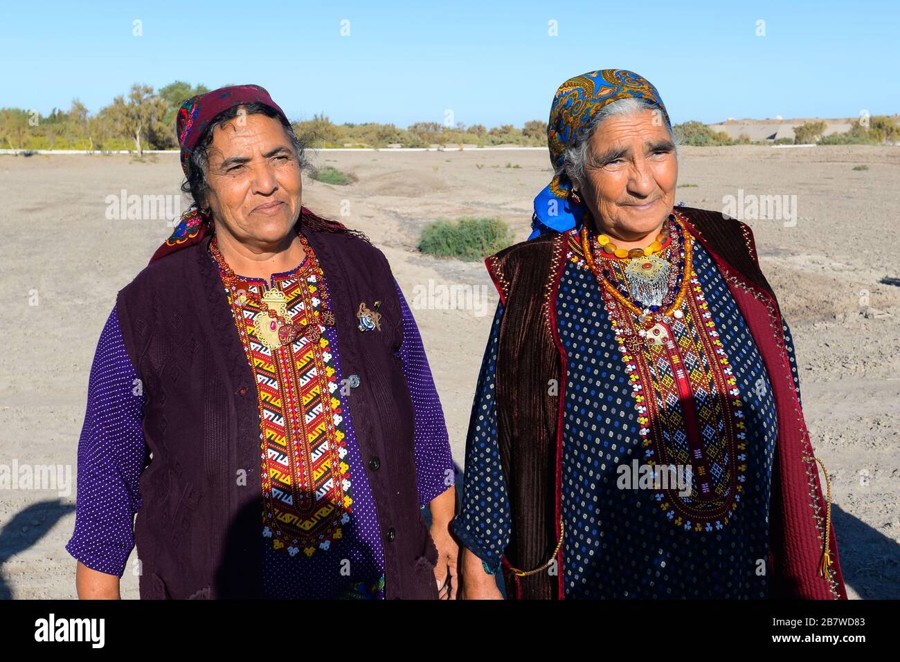 Two posing old woman wearing traditional clothes for rural area in Central Asia in Kunya Urgench, Turkmenistan. Colorful Turkmen robe and scarf. Stock Photo