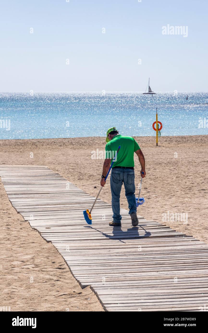 Sweeping the boardwalk across the beach at Caleta de Fuste on the east coast of the Canary Island of Fuerteventura Stock Photo