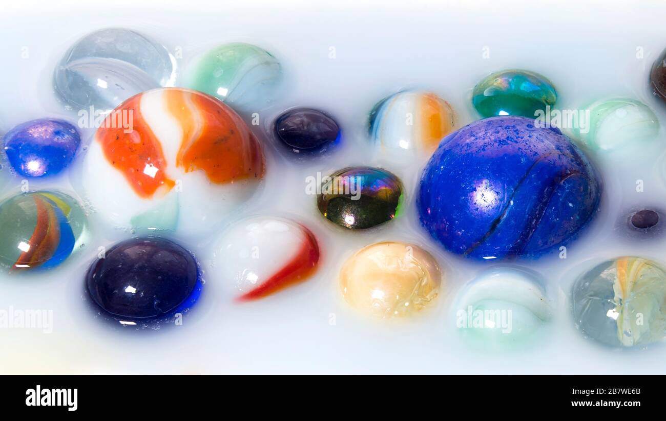 Multicolored marbles inside milk as abstract background Stock Photo