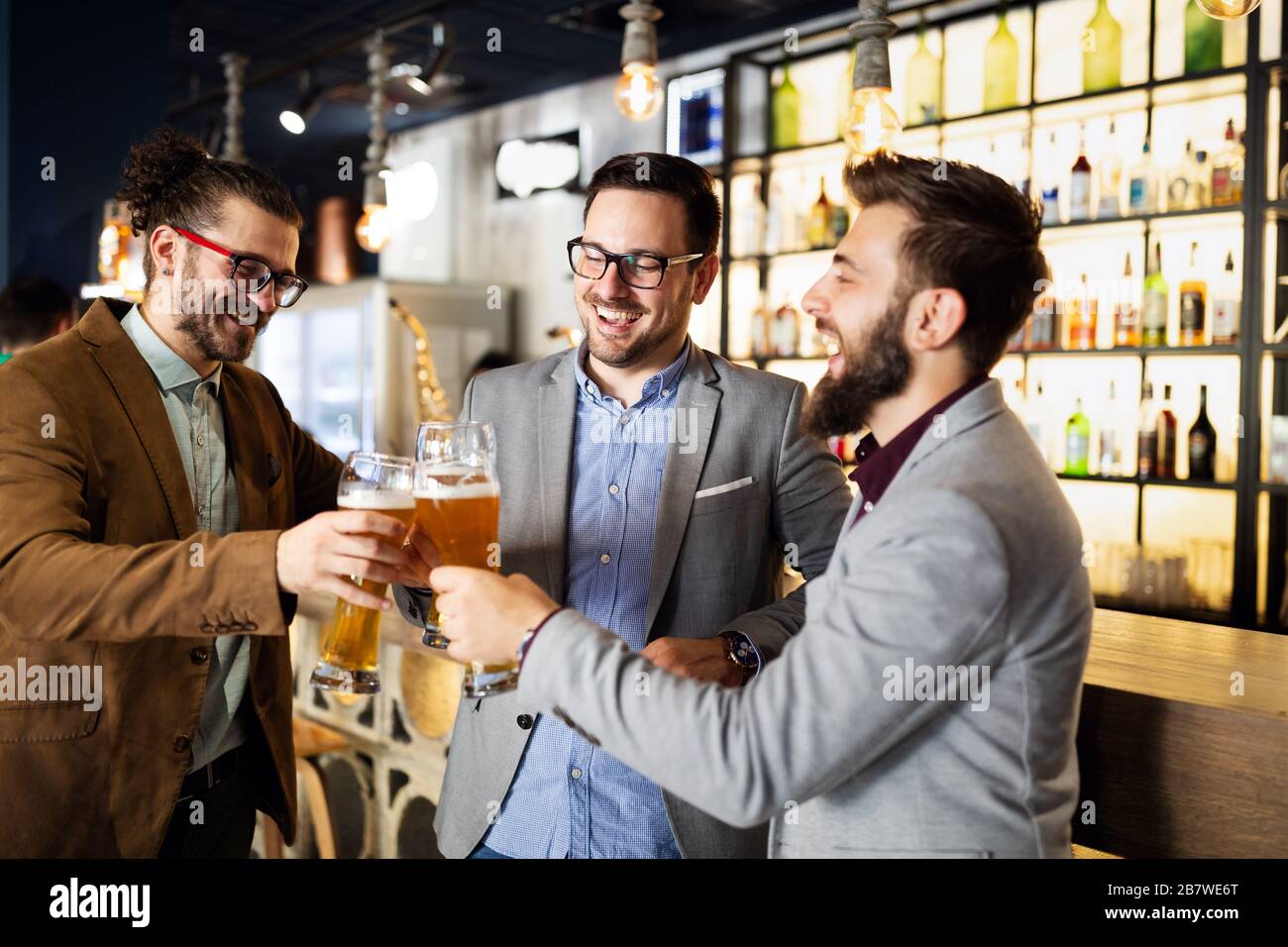 Happy young business men talking and drinking beer in a pub Stock Photo