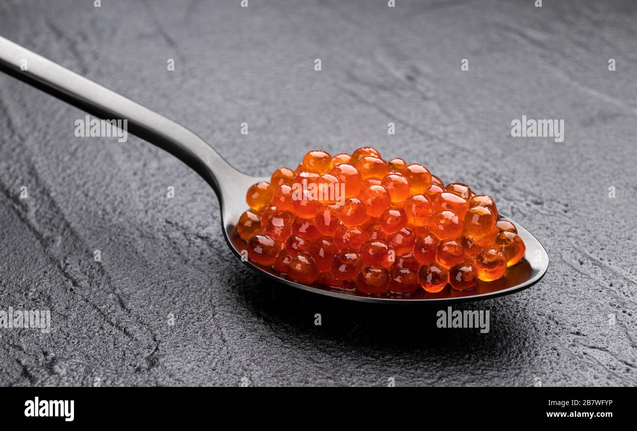 Red caviar in spoon close-up on black stone background Stock Photo
