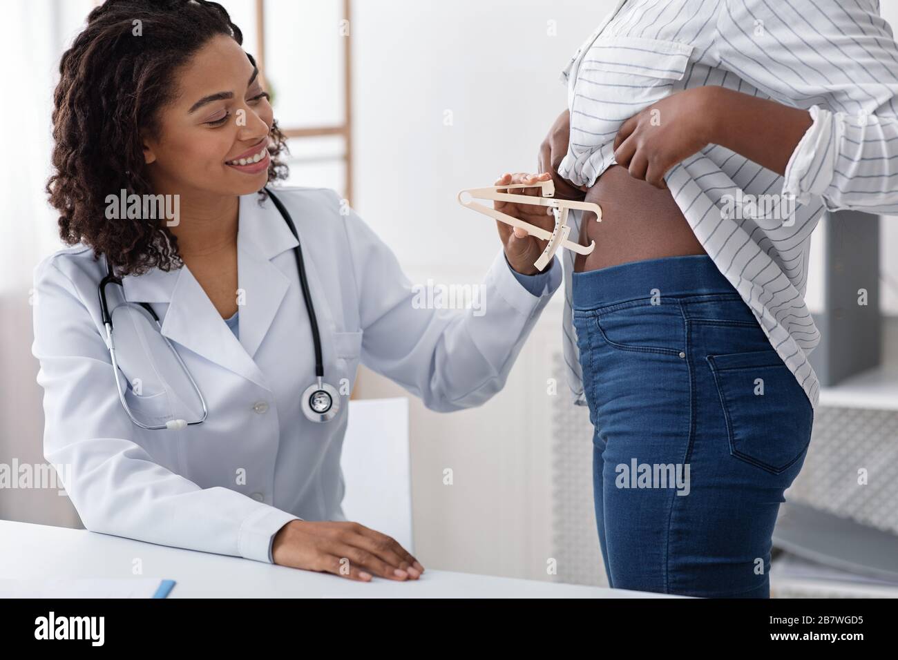 Doctor checking patient body fat index with caliper Stock Photo