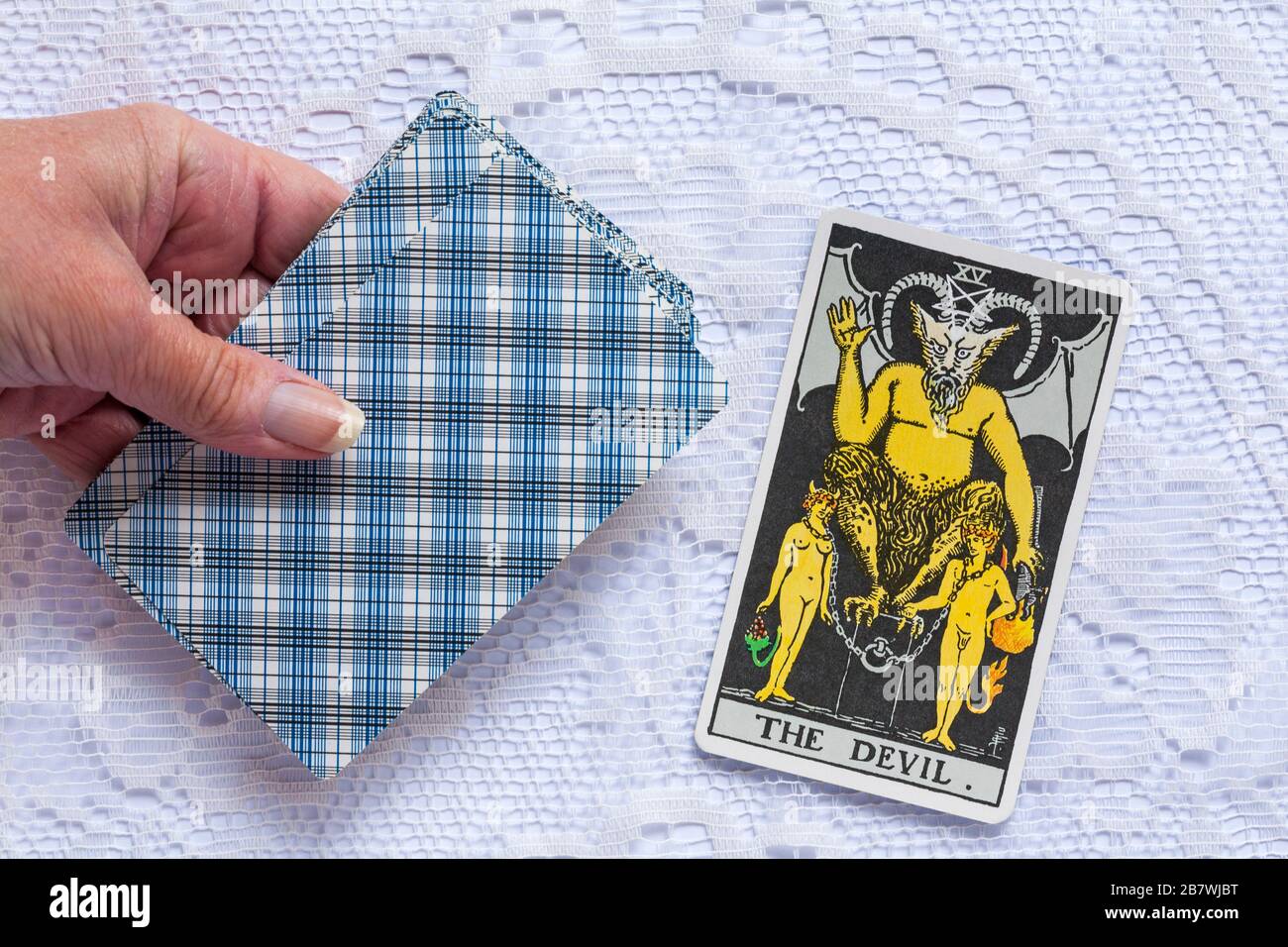hand holding Rider Tarot Cards designed by Pamela Colman Smith under supervision of Arthur Edward Waite with The Devil tarot card upturned Stock Photo
