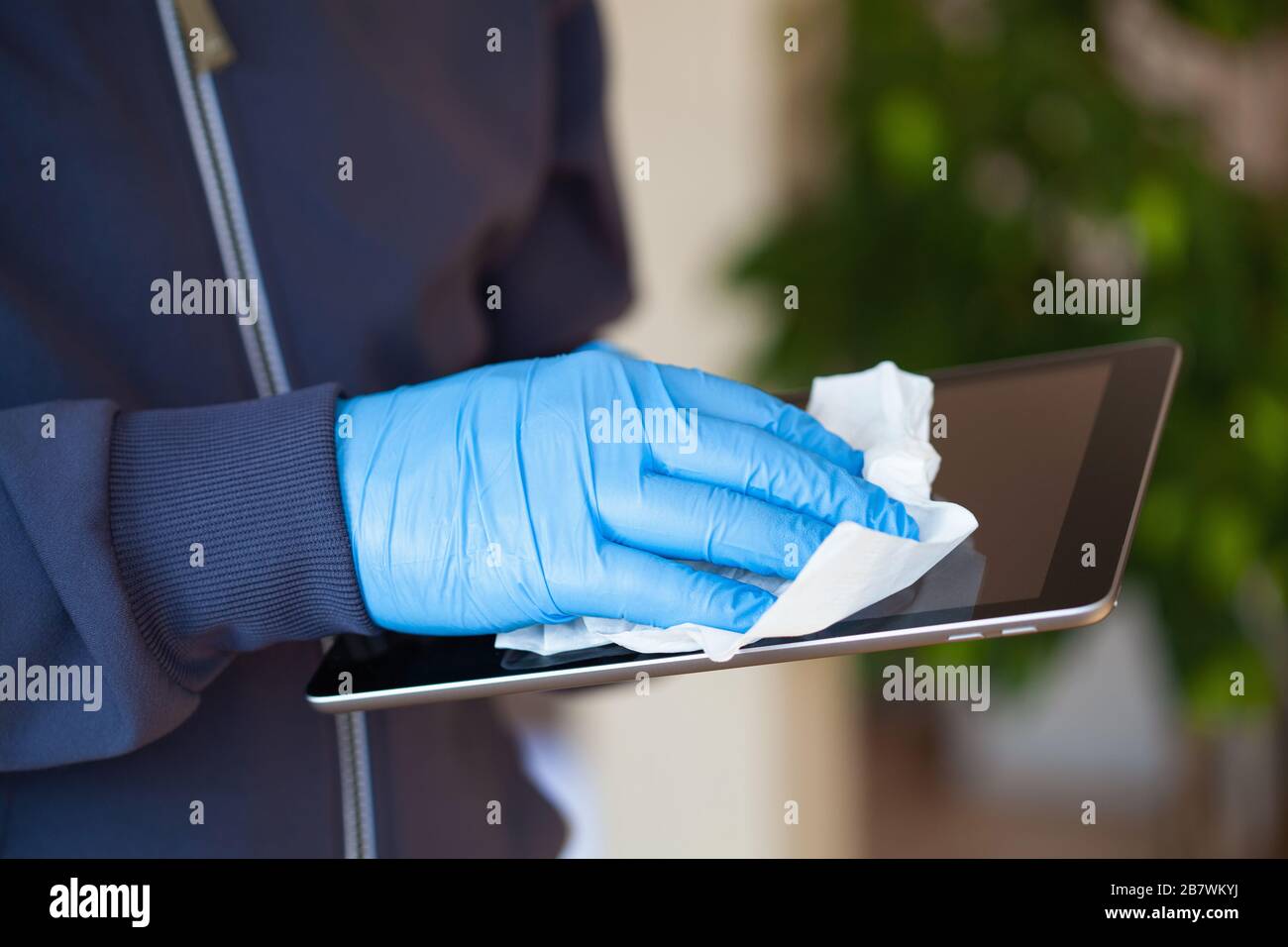 man hands in gloves disinfecting tablet computer screen, eliminate germs coronavirus bacteria Stock Photo