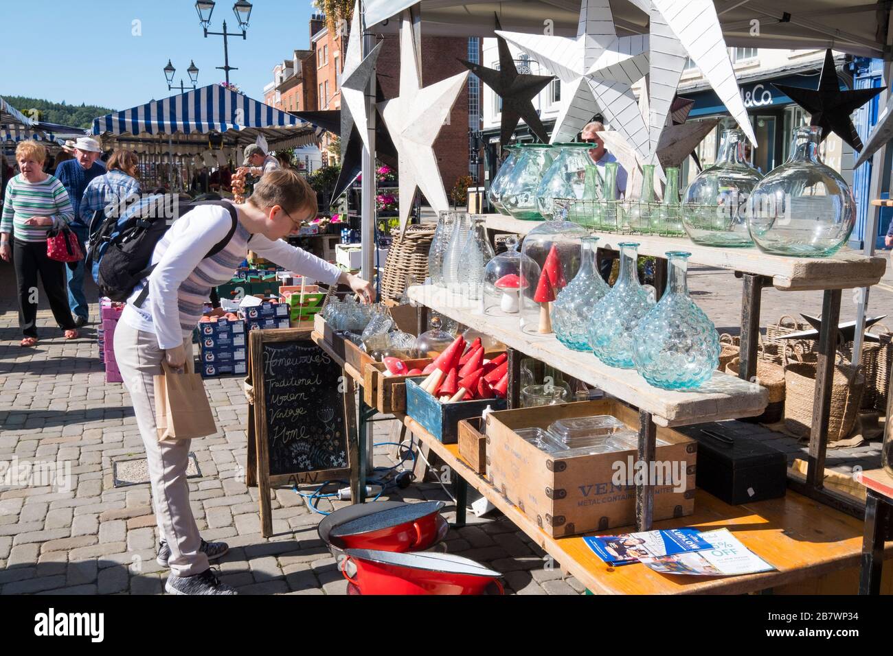 A woman shopper sorting through decorative items on a stall at Ludlow market, Shropshire, England, UK Stock Photo