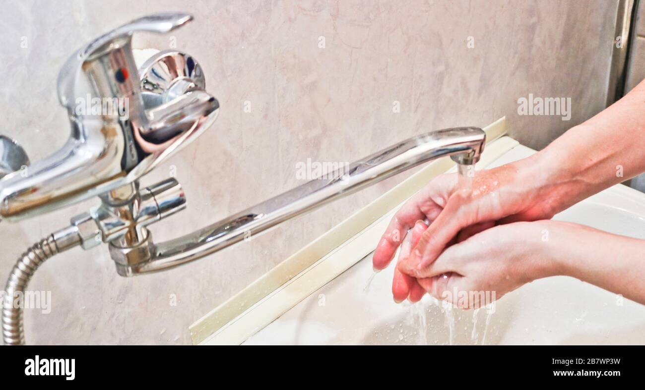 A woman washes her hands with soap and water from a water tap. Hygiene ...