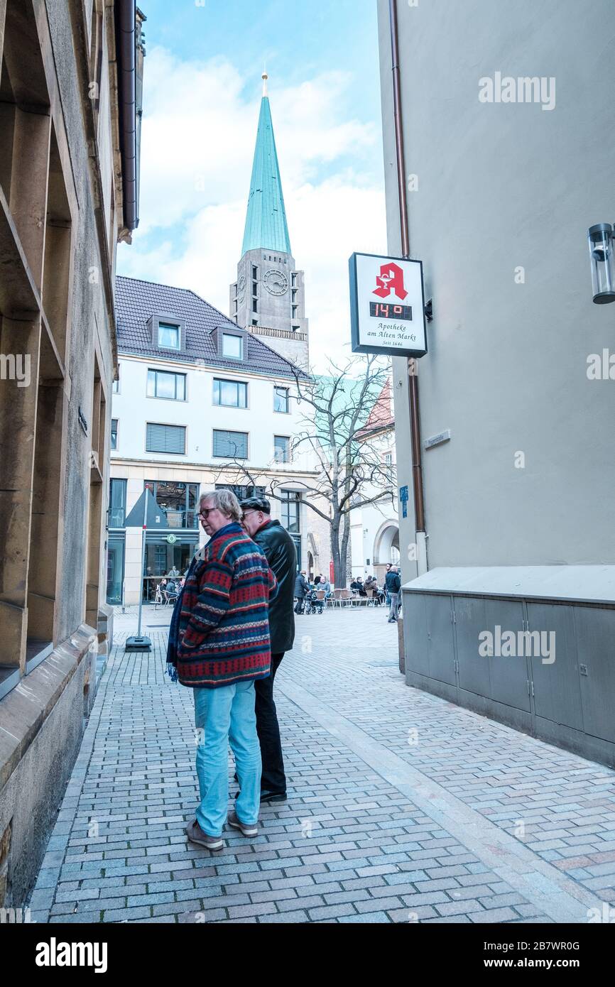 a couple window shopping on a sunny sunday afternoon in the old town of Bielefeld, Germany with a church in the background Stock Photo