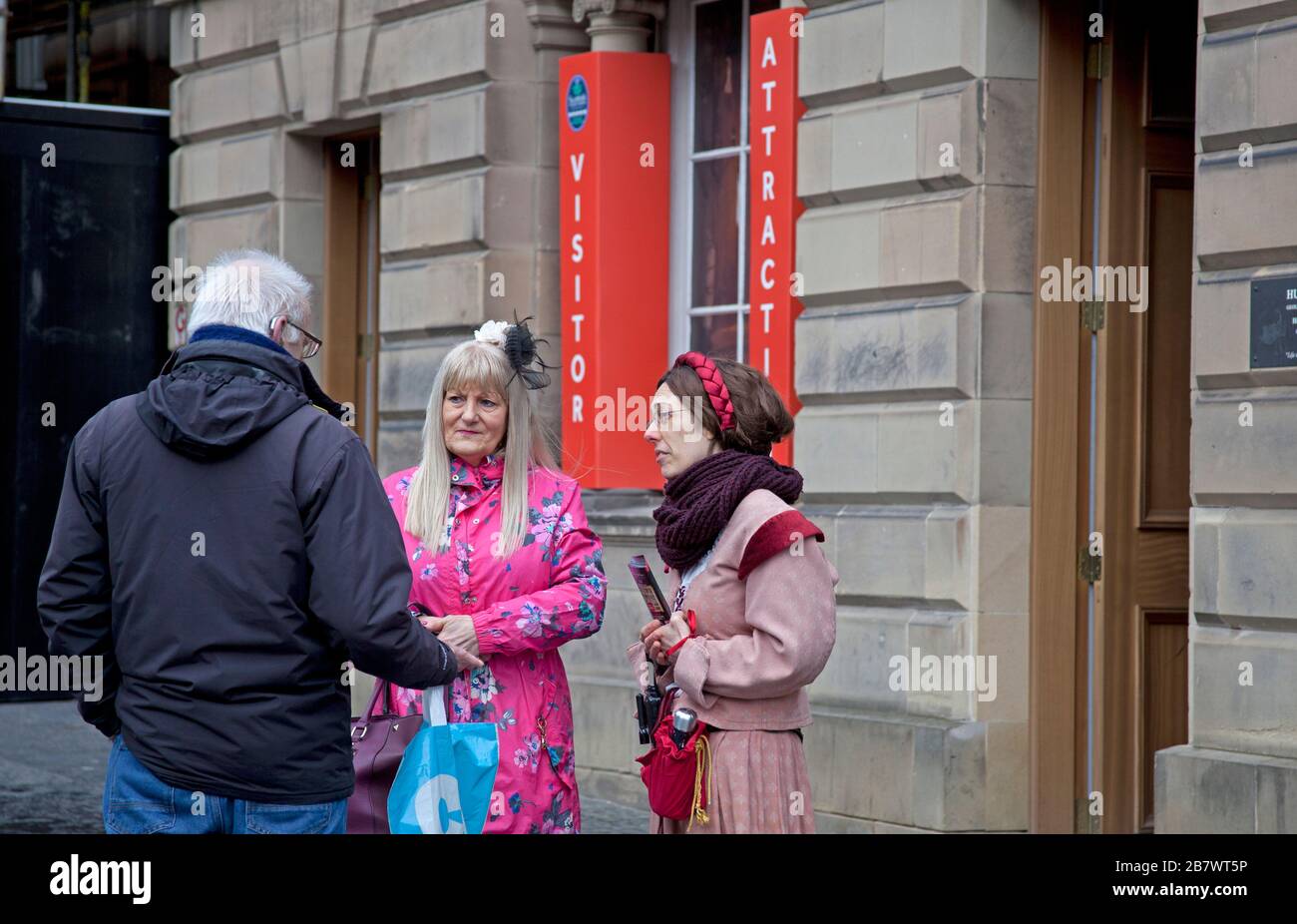 Edinburgh, Scotland, UK. 18th March 2020.  Covid-19 not stopping tourists walking around the Royal Mile this couple chat to one of the staff from Mary Kings Close visitor attraction. Stock Photo