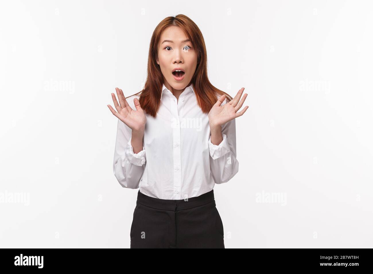 Portrait of shocked and amazed asian office lady gasping and staring startled camera, raise hands astonished gossiping about something astounding Stock Photo