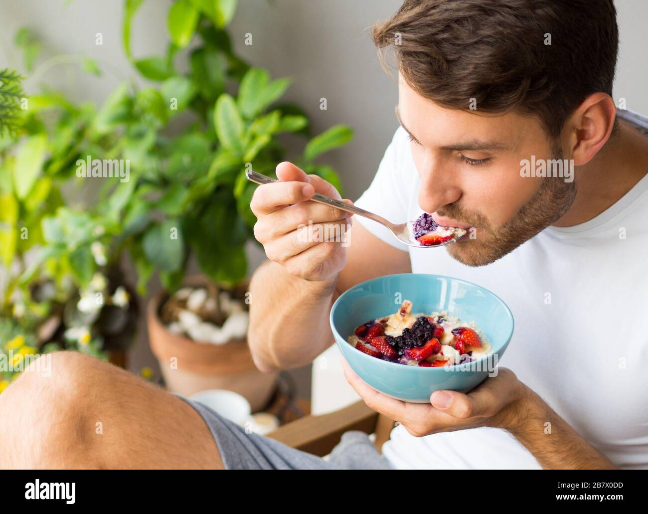 Beautiful young caucasian man with a beard having a healthy vegan breakfast outdoors. Stock Photo