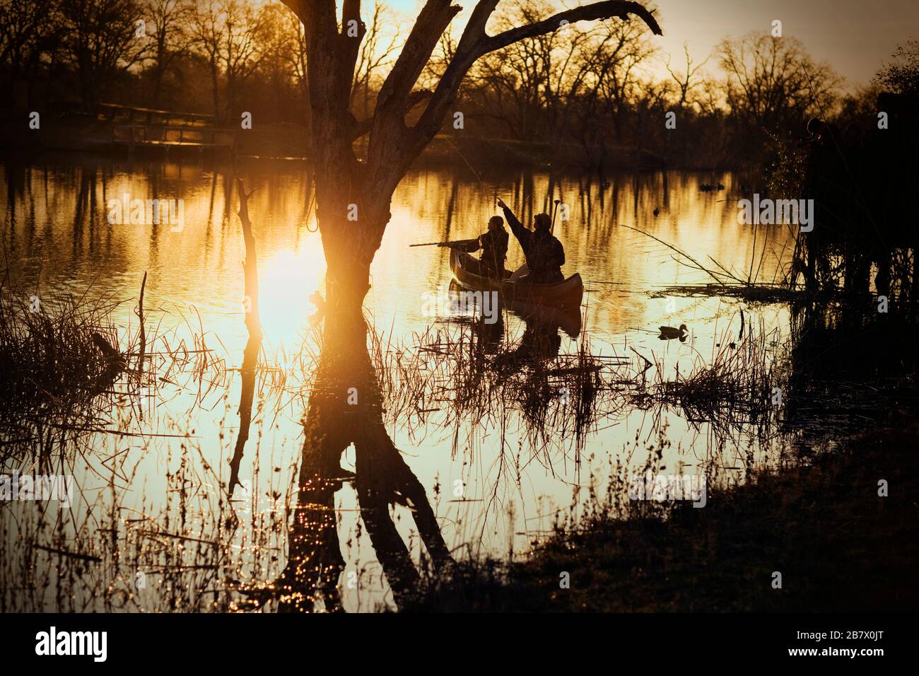 Couple duck shooting on a lake at sunset. Stock Photo
