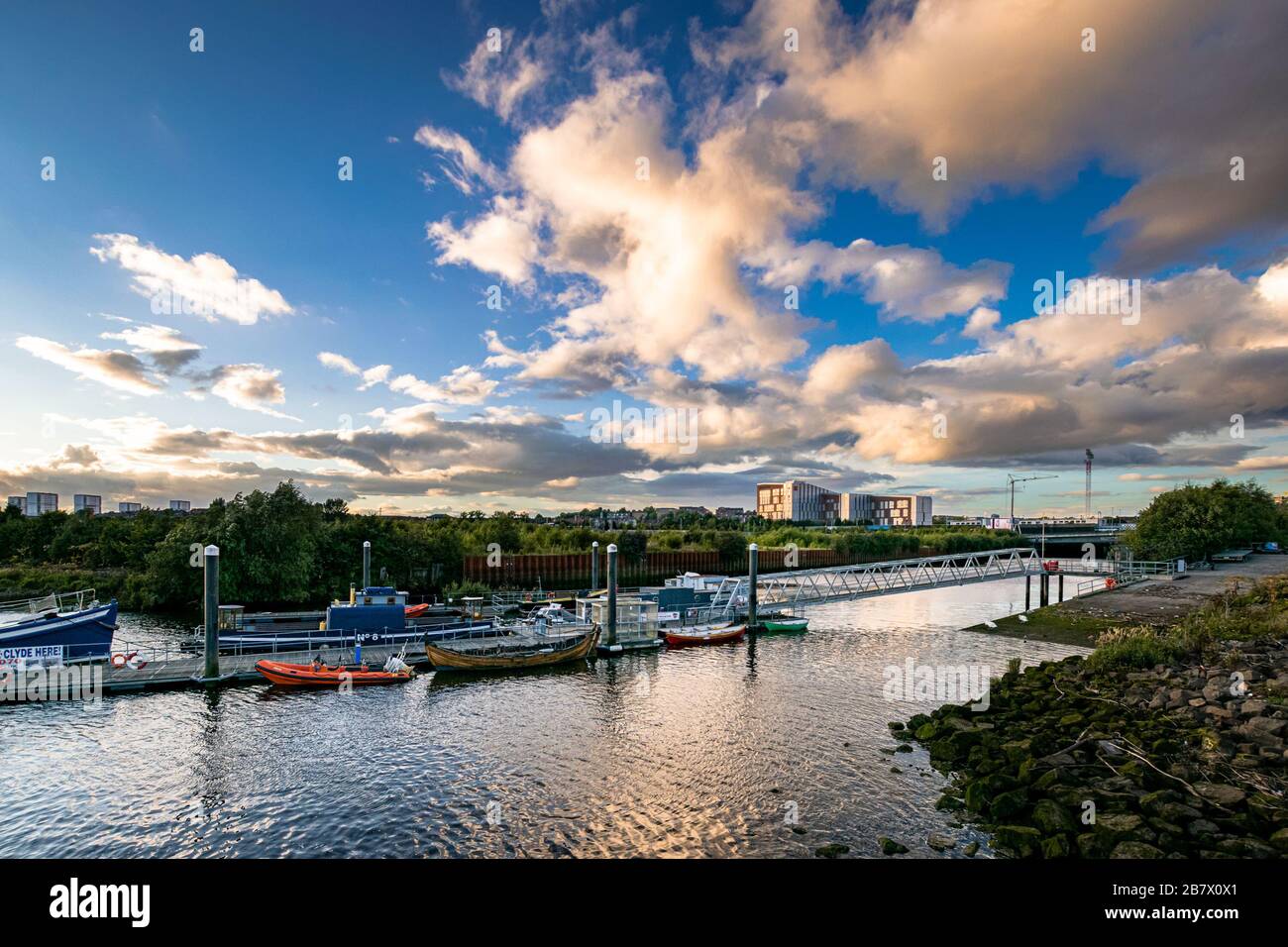 Govan Ferry jetty on River Clyde at sunset with blocks of flats on the horizon. Wide angle urban scene. Stock Photo