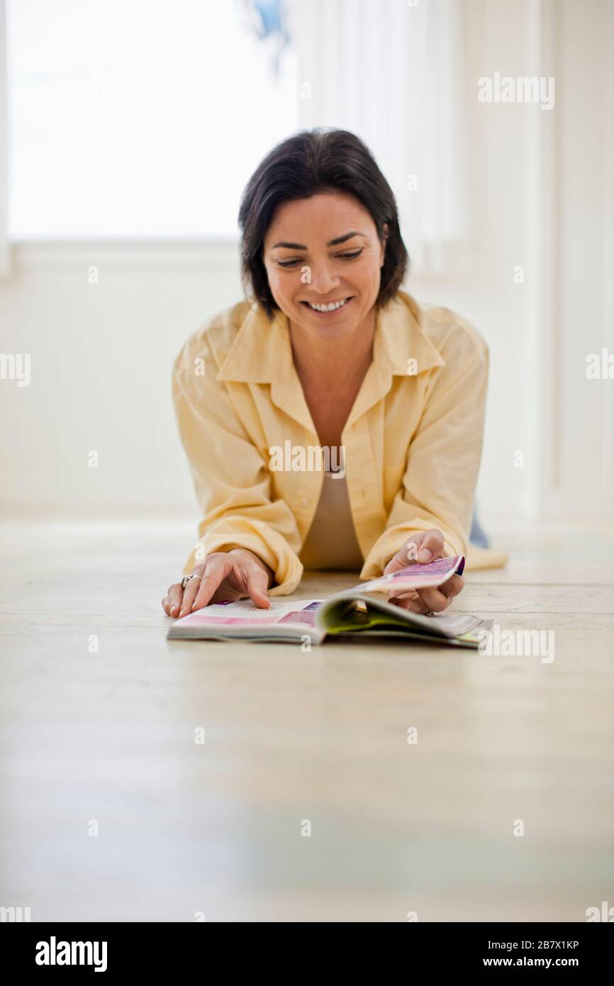 Smiling mid adult woman reading a book in her pajamas. Stock Photo