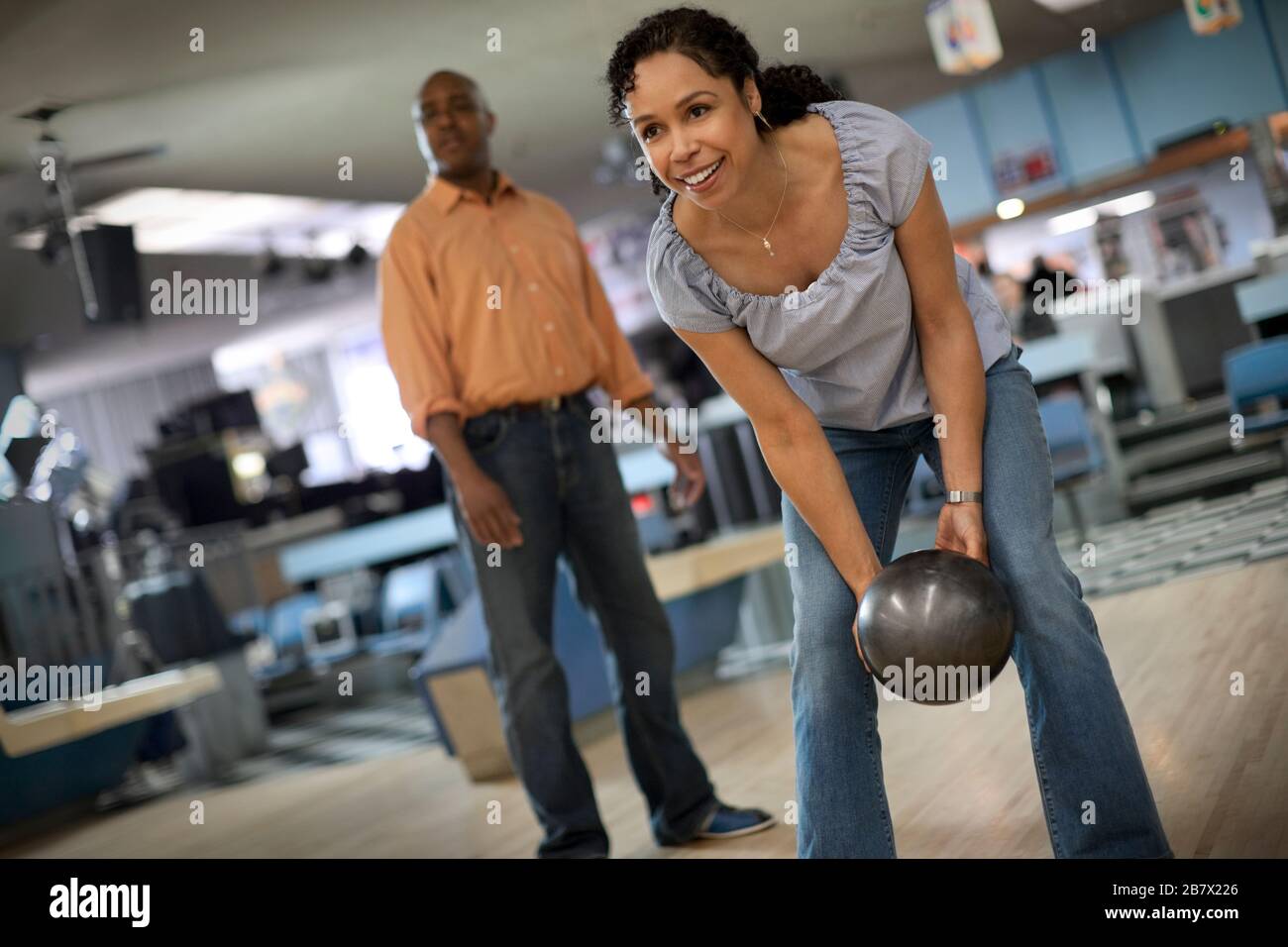 Smiling mid adult woman throwing a bowling ball. Stock Photo
