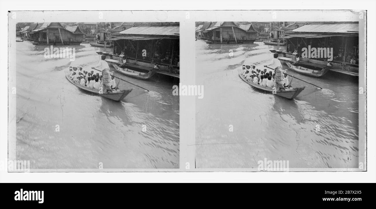 Creek of Stung Sangkae river in the Battambang province  of Cambodia. Cham school boys being transported in a traditional water taxi. Swimming warehouses offer their goods. Stereoscopic photograph from around 1910. Picture on dry glass plate from the Herry W. Schaefer collection. Stock Photo