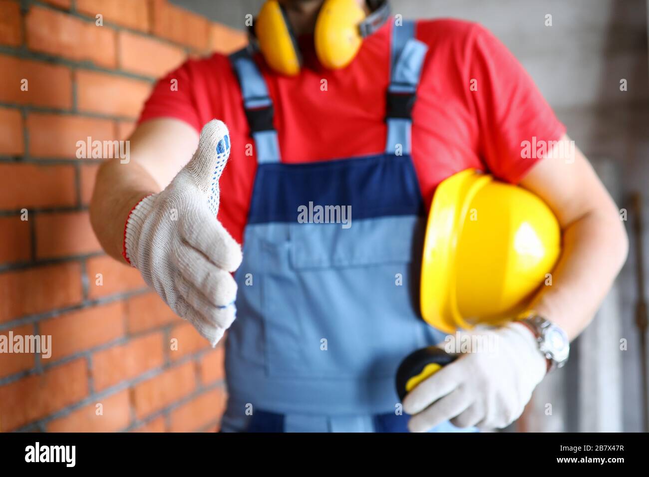 Worker at construction site offering hand to shake Stock Photo